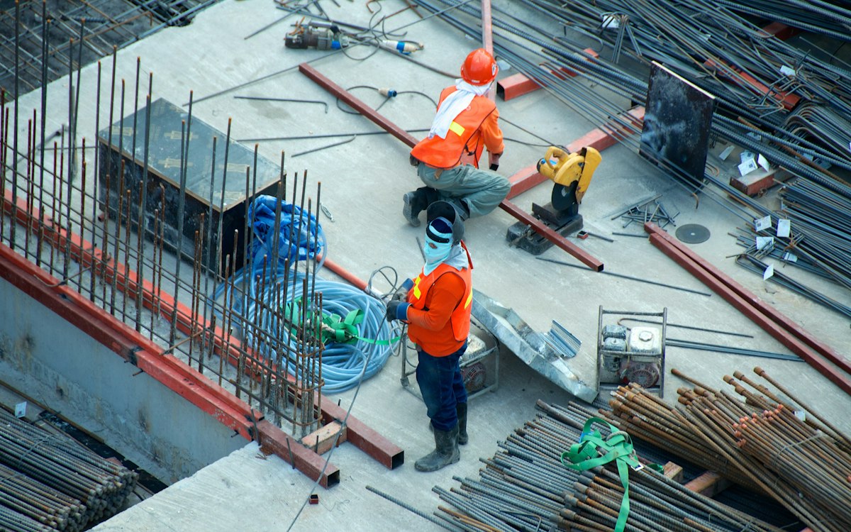Handwerker mit Schutzhelmen arbeiten auf einer Baustelle mit Bewehrungsstahl