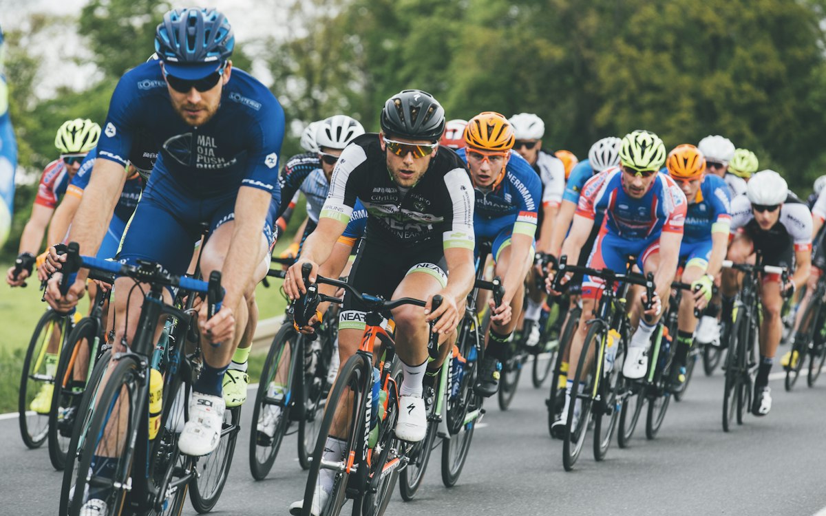 Radsportgruppe in Vereinstrikots bei einem Straßenrennen