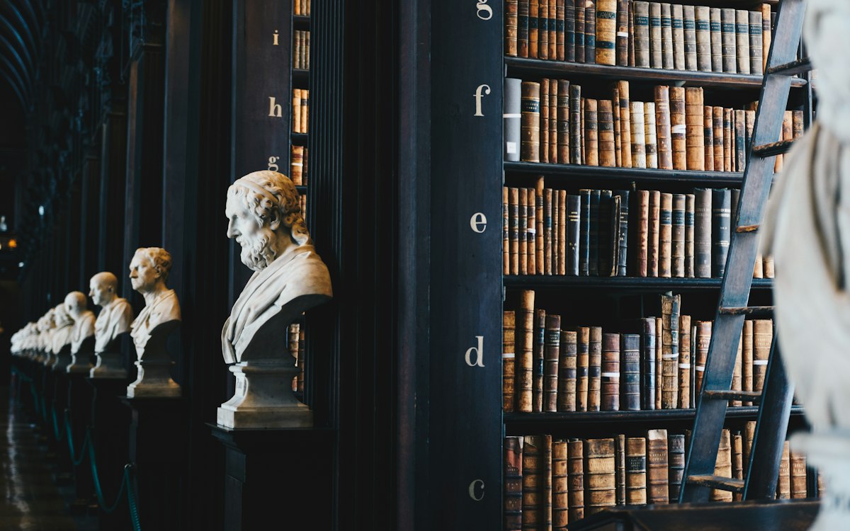 Historische Bibliothek mit Bücherregalen und Marmorbüsten – Inkassodienstleister oder Rechtsanwalt beauftragen