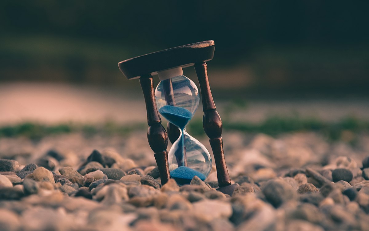 Sanduhr mit rinnendem blauen Sand – Verjährungsfristen von Forderungen laufen ab
