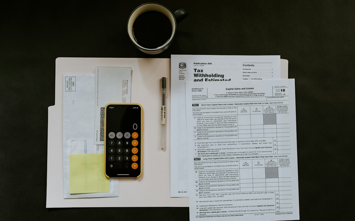 Formulare, Smartphone mit Taschenrechner-App und Kugelschreiber – Verzugszinsen korrekt berechnen